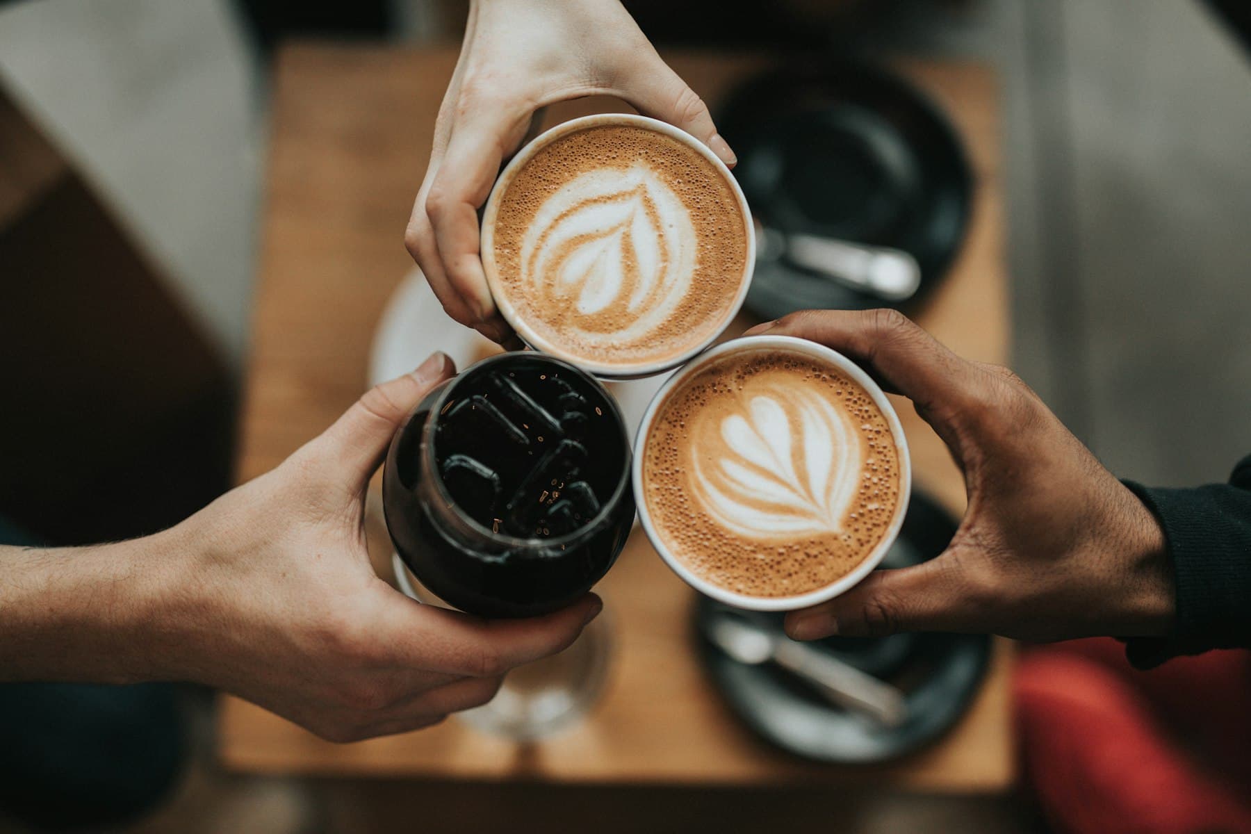 Two people raising warm cups of coffee together